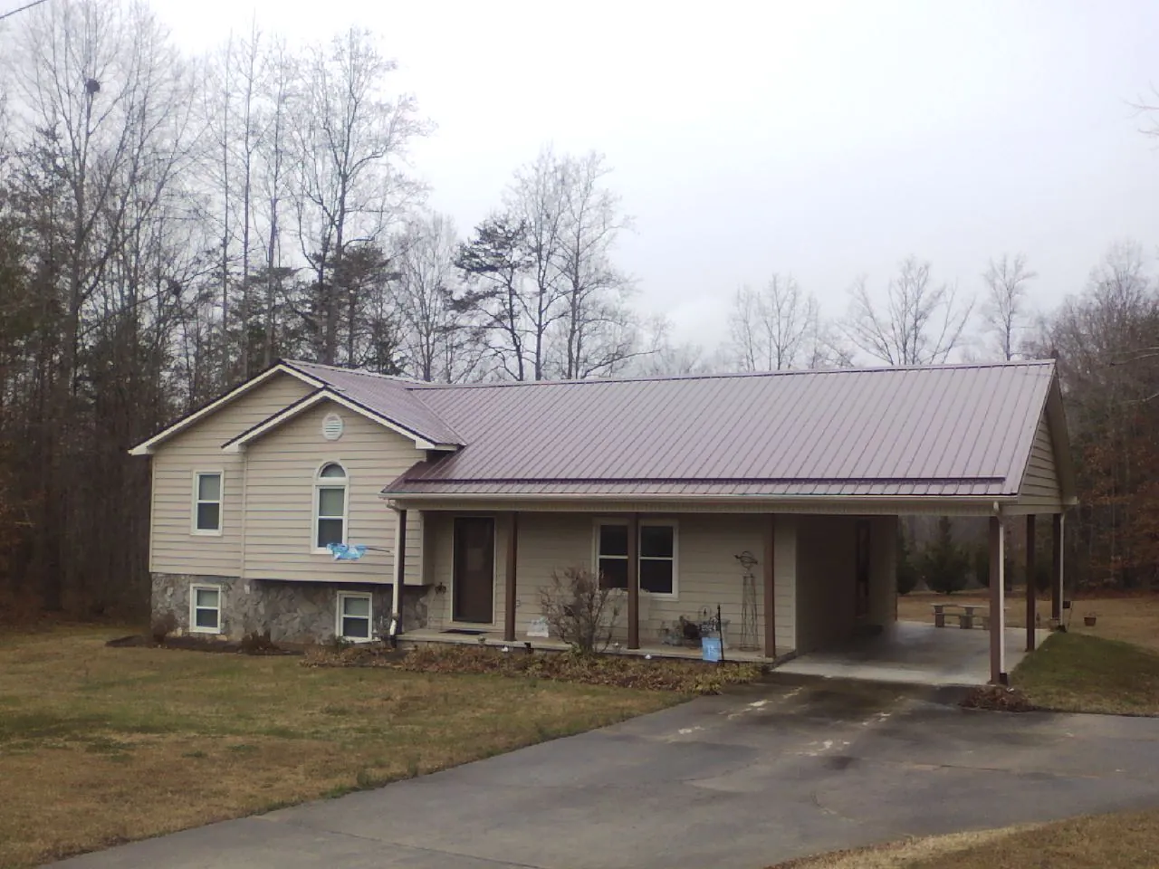 Burgundy metal roof on a tan split level home with an attached carport in Newport